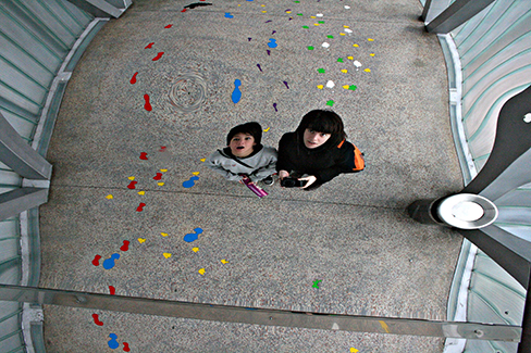 A photograph of two children staring at themselves in a distorting mirror.